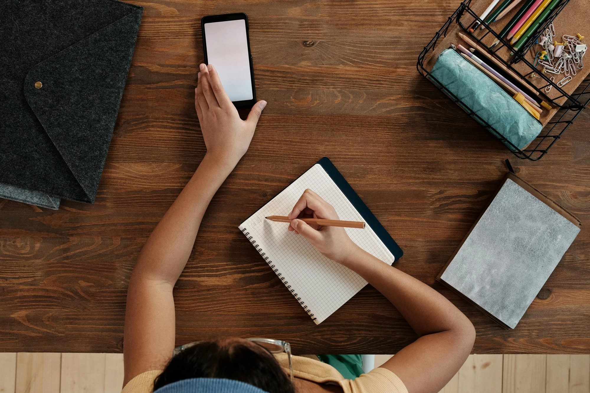A child studying at a desk with a phone and a notebook